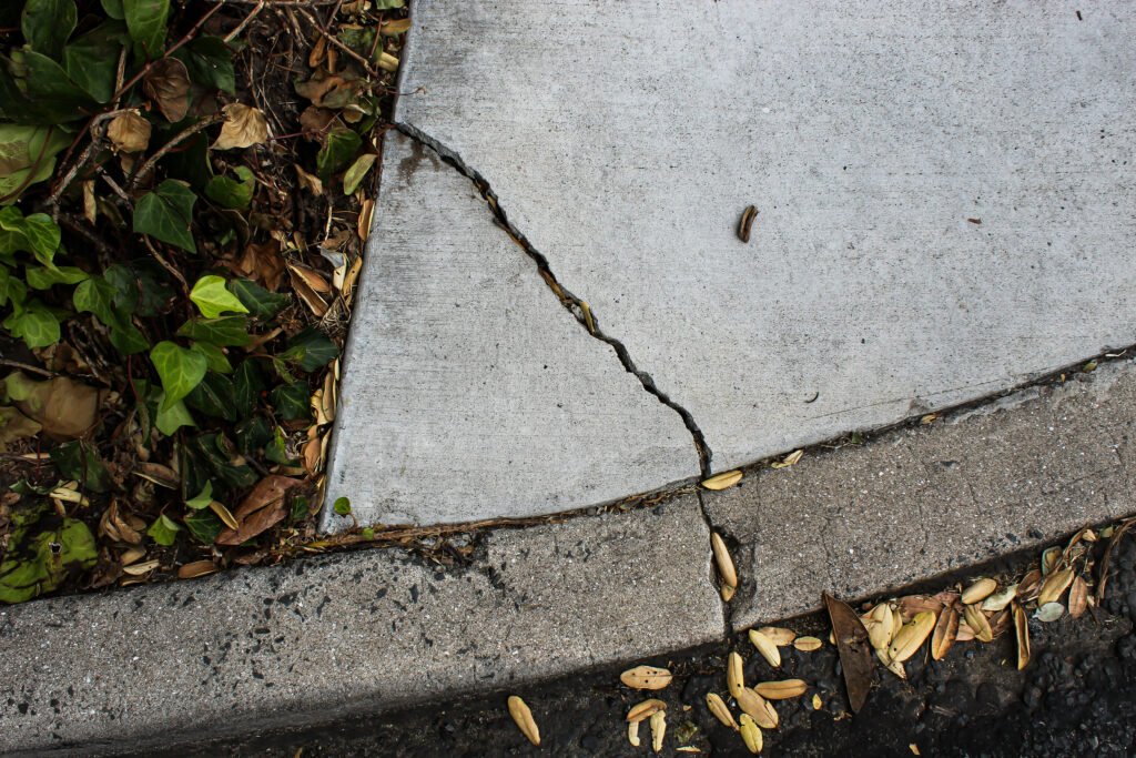 A crack on the end of a concrete driveway, leading into the curb
