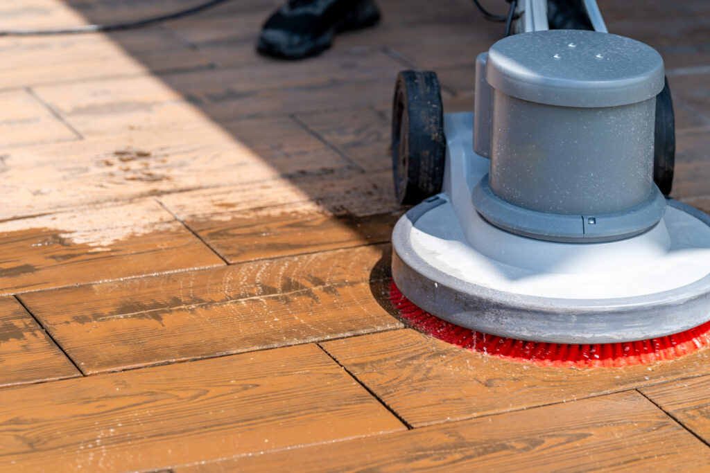 A person uses a professional scrubber to gently wash a stamped patio made to mimic hardwood