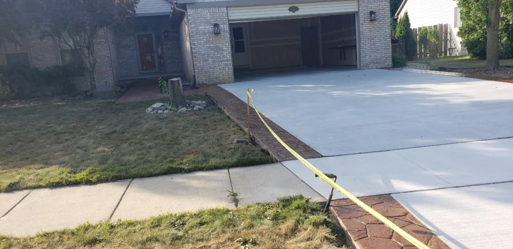 New concrete driveway with colored, stamped concrete on both sides.