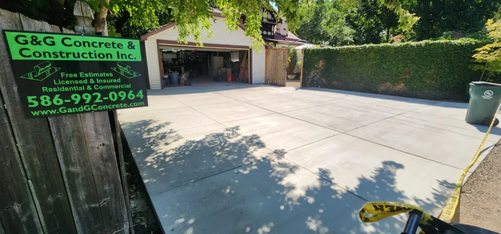 New concrete driveway leading to an open garage, with a G&G Concrete & Construction Inc. sign on the left.