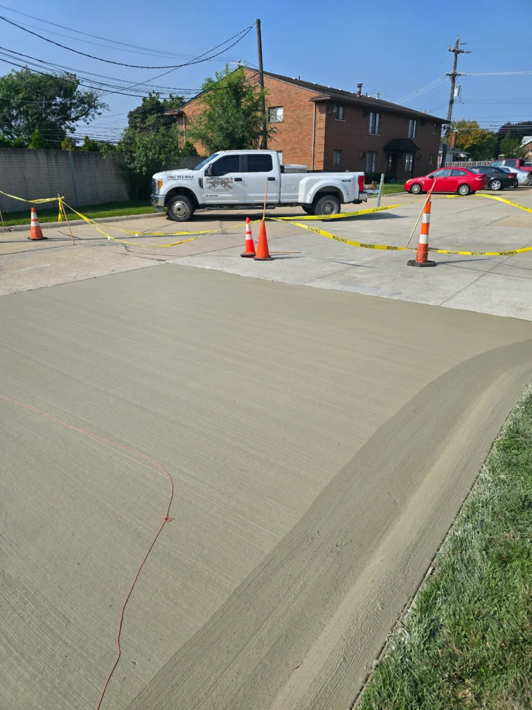 Freshly poured concrete driveway section, blocked by caution tape & cones, with a G&G Concrete truck nearby.