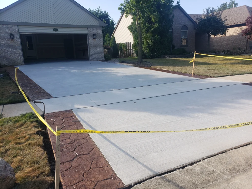 New concrete driveway with colored, stamped concrete on both sides.
