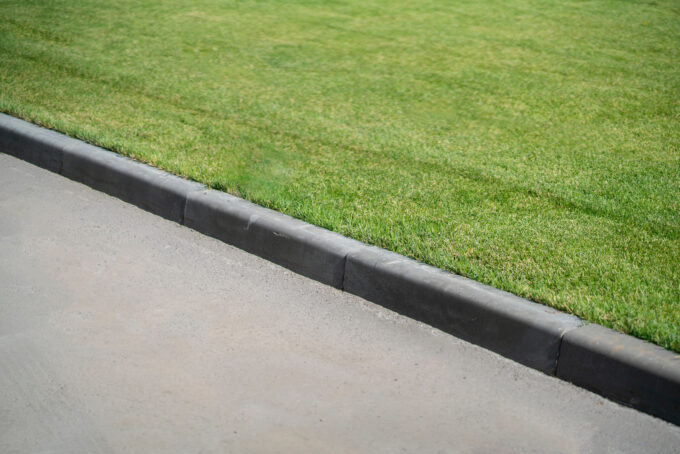 A concrete curb in front of a grassy lawn