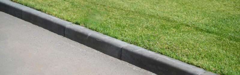 A concrete curb in front of a grassy lawn