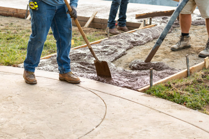 Construction Worker Pooring Wet Deck Cement Into Wooden Frame