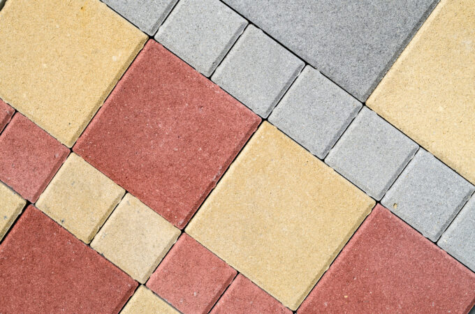 Concrete pavers in various colors, including off-white/tan, red, and gray.