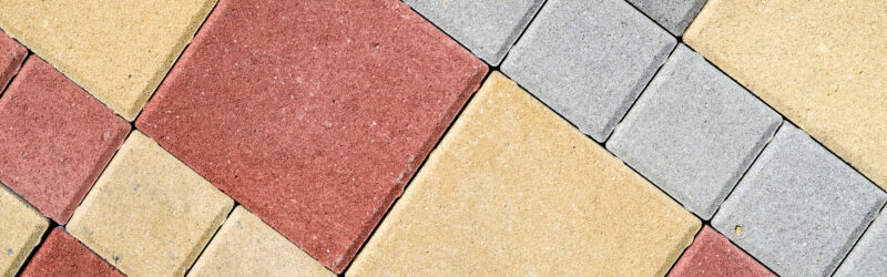 Concrete pavers in various colors, including off-white/tan, red, and gray.